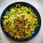 Delicious Indian poha with peanuts and herbs on a vibrant plate.