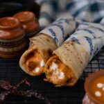 Close-up of spicy tandoori chicken rolls with sauce and spices, perfect for food enthusiasts.