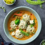 Top view of dumplings in a vibrant curry sauce with vegetables, perfect for traditional Asian cuisine lovers.
