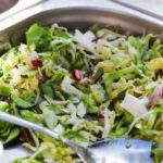 Close-up of fresh vegetable salad with cucumbers, cabbage, and radishes, served in a stainless steel tray.